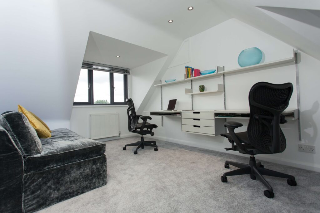 A Home Office Loft Conversion with two chairs, shelving, and sofa seating