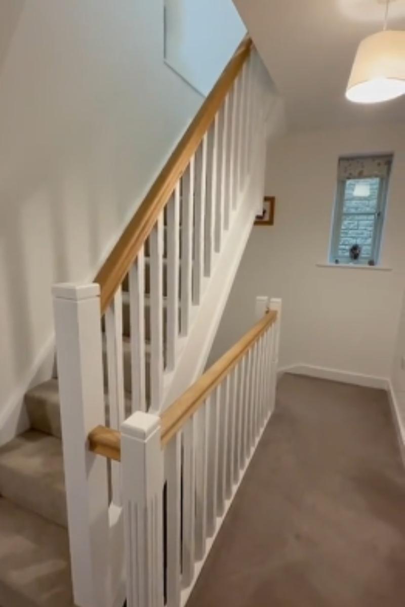 A staircase finished in white with a natural wooden handrail