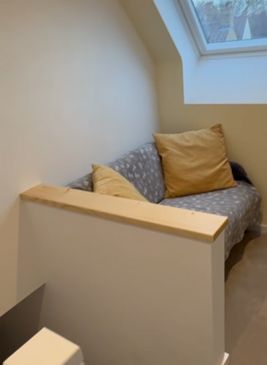 A relaxation space on a landing with a two seater sofa underneath a VELUX window