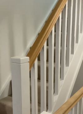Closeup of a newly completed staircase painted white with a natural wooden handrail