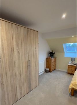 A wooden wardrobe in a bedroom with a single VELUX window
