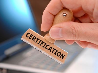 A hand holding a rubber stamp with the word certification written on it