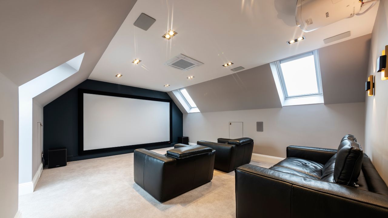 Loft conversion with three VELUX windows, three leather sofas, and a wall-sized home cinema screen